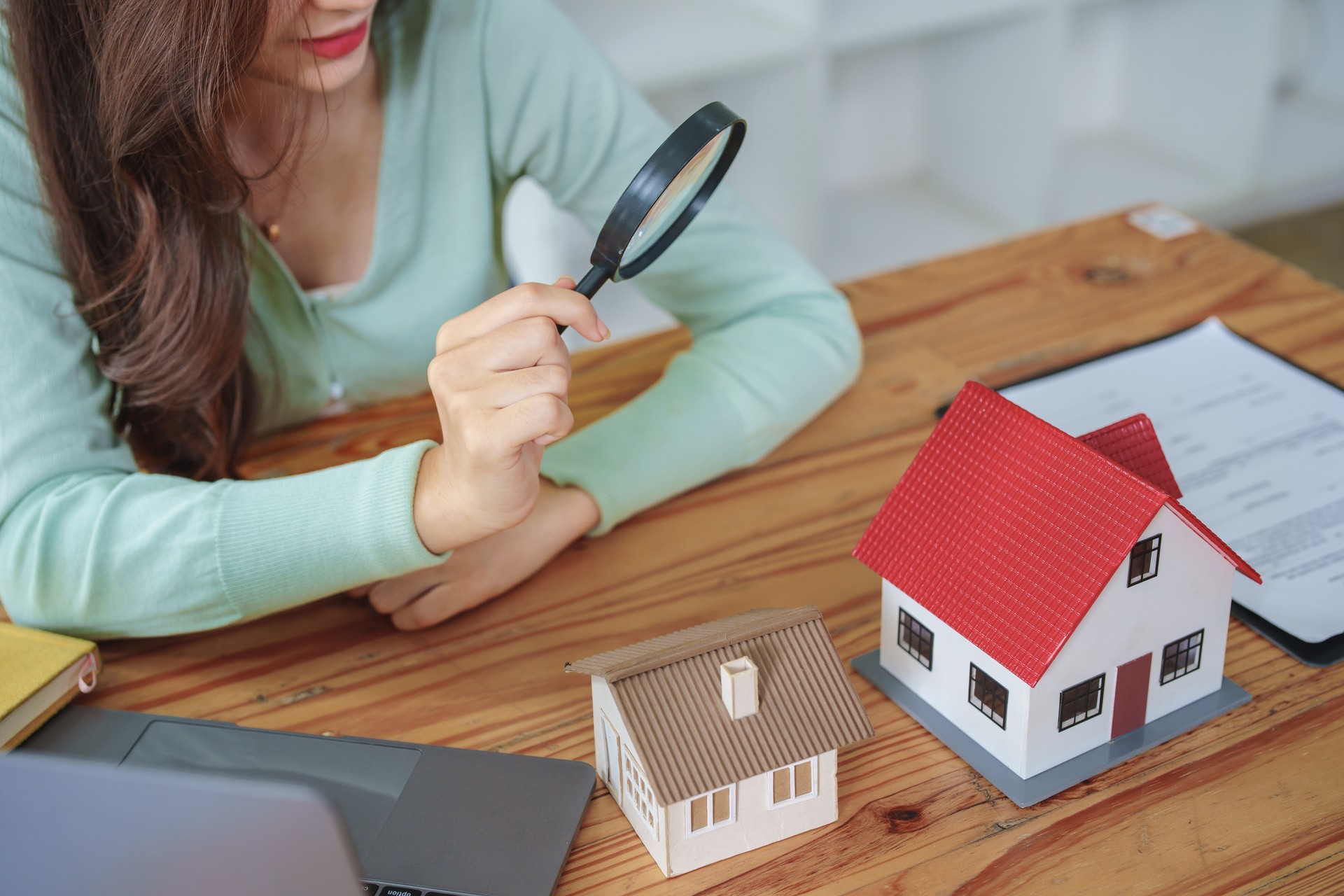 Customer holding a magnifying glass to select a house model, residential inspection concept